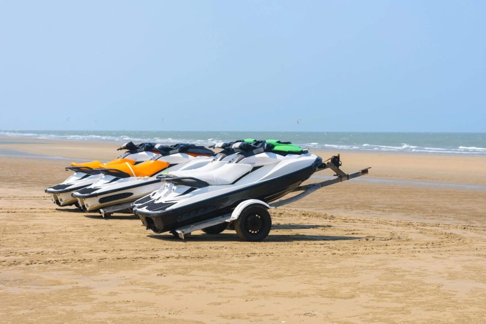 A row of jet skis parked on the beach.